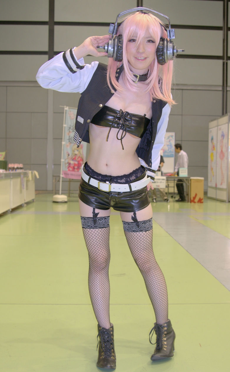 Asian Pink-Haired Cosplay Girl wearing Black Fishnet Stockings, Black Latex Bra and Shorts