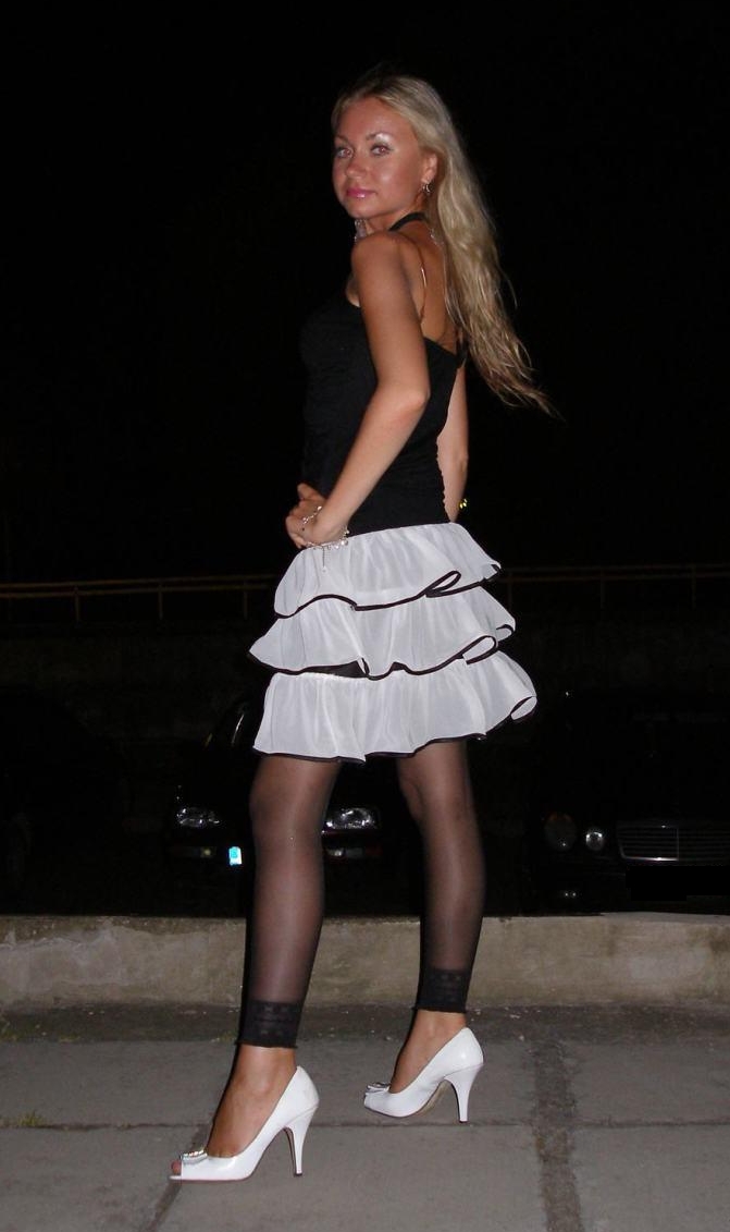 Blonde Young Woman wearing Black Sheer Leggings and White Pleated Mini Skirt
