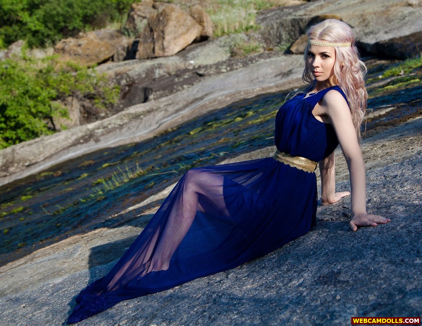 Blonde Girl sitting on Rocks in Blue Long See Through Dress on Webcamdolls