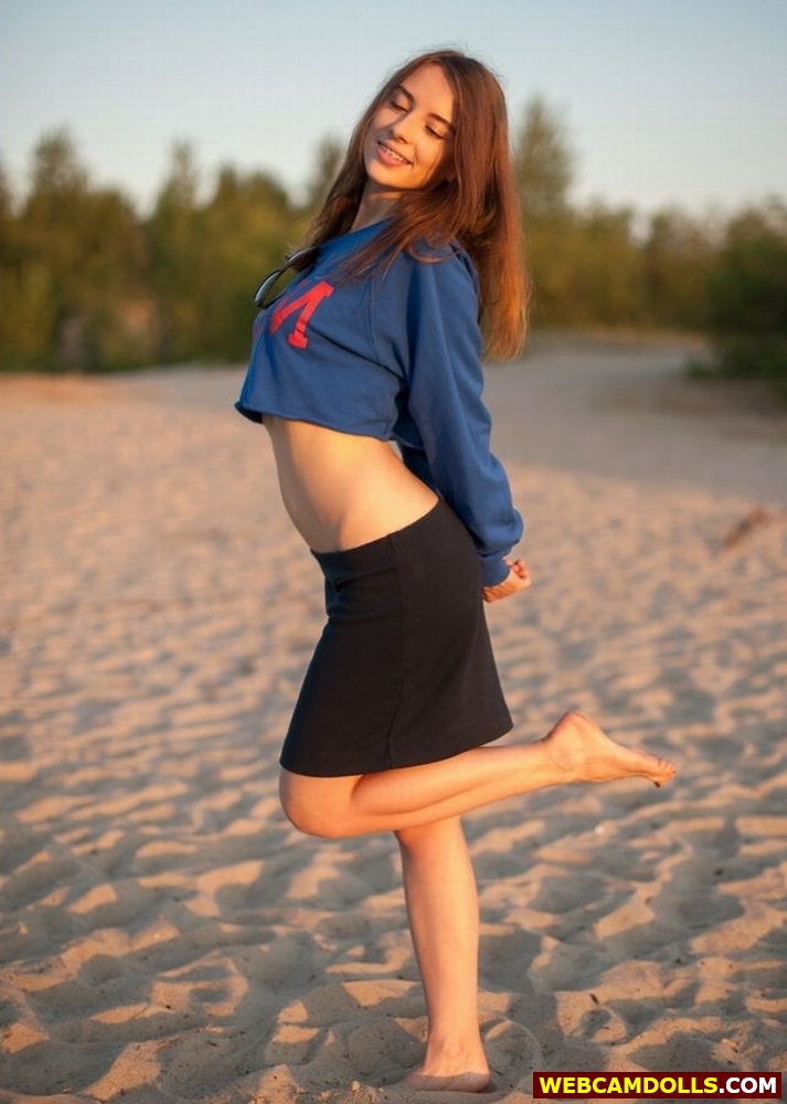 Auburn Teen Girl standing with Bare Feet in Sand in Black Mini Skirt on Webcamdolls