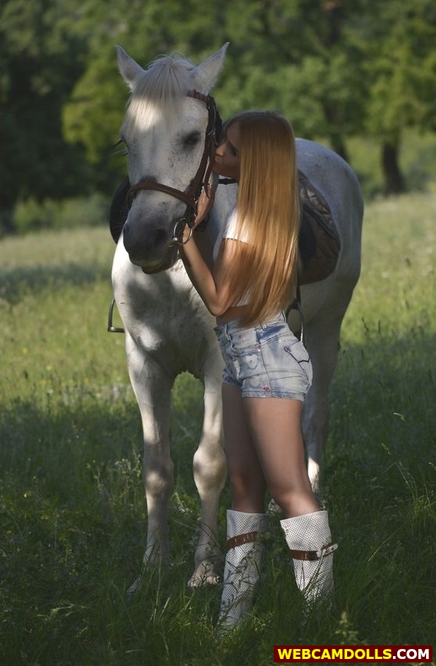 Blonde Young Horsewoman in Blue Denim Shorts and White Boots on Webcamdolls