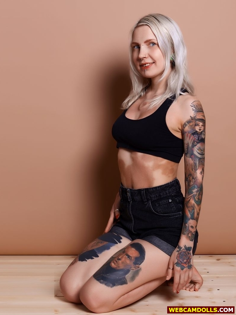 Blonde Tattooed Girl kneeling in Denim Shorts and Sport Bra on Webcamdolls